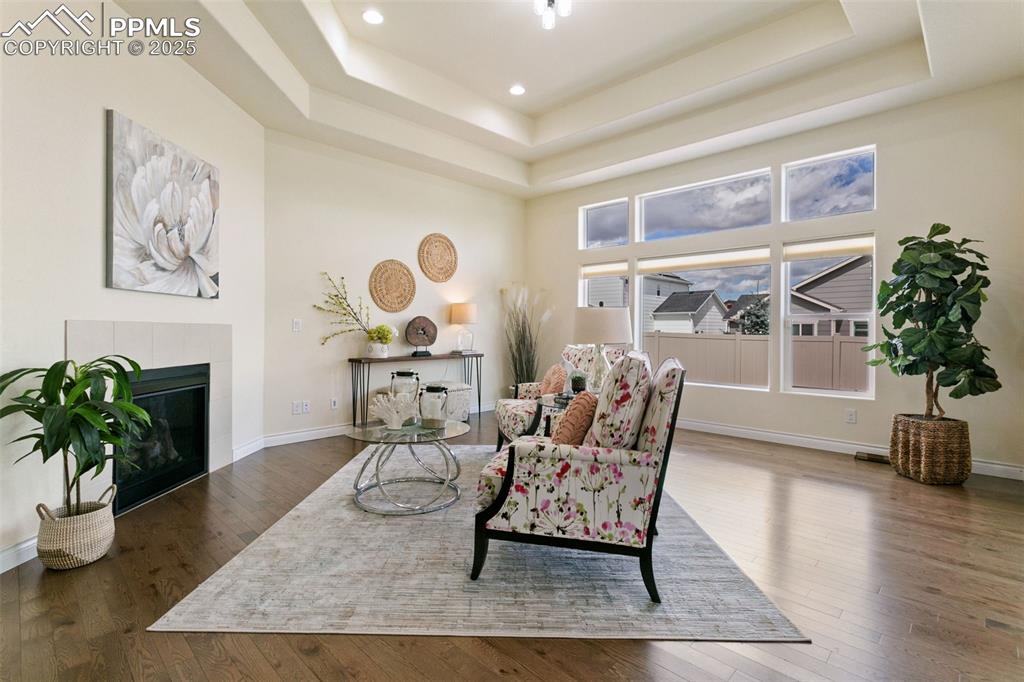 Image 5 of 49: Living area with a tray ceiling, hardwood / wood-style flooring, a fireplac
