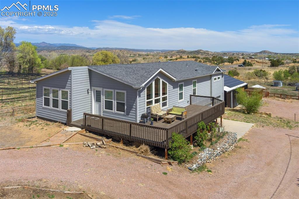 Caption: Back of property featuring a deck with mountain view, driveway, and a shingled roof