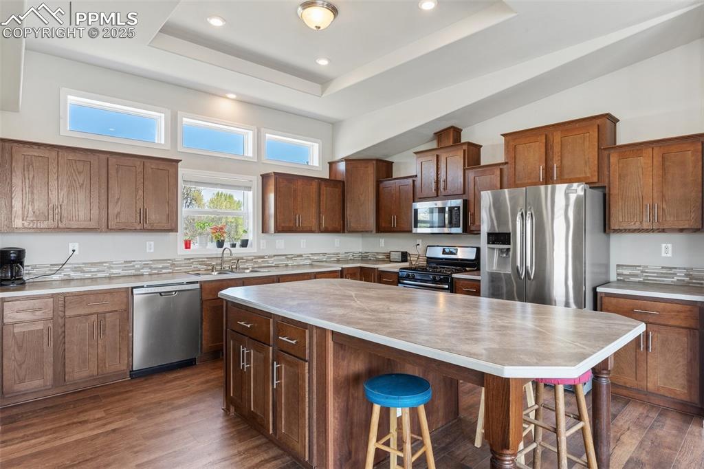 Image 11 of 50: Kitchen with a kitchen breakfast bar, a sink, a high ceiling, light counter