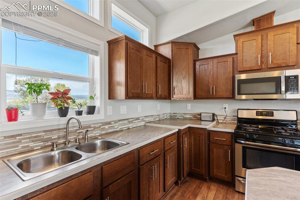 Image 13 of 50: Kitchen featuring light countertops, a sink, dark wood-type flooring, decor