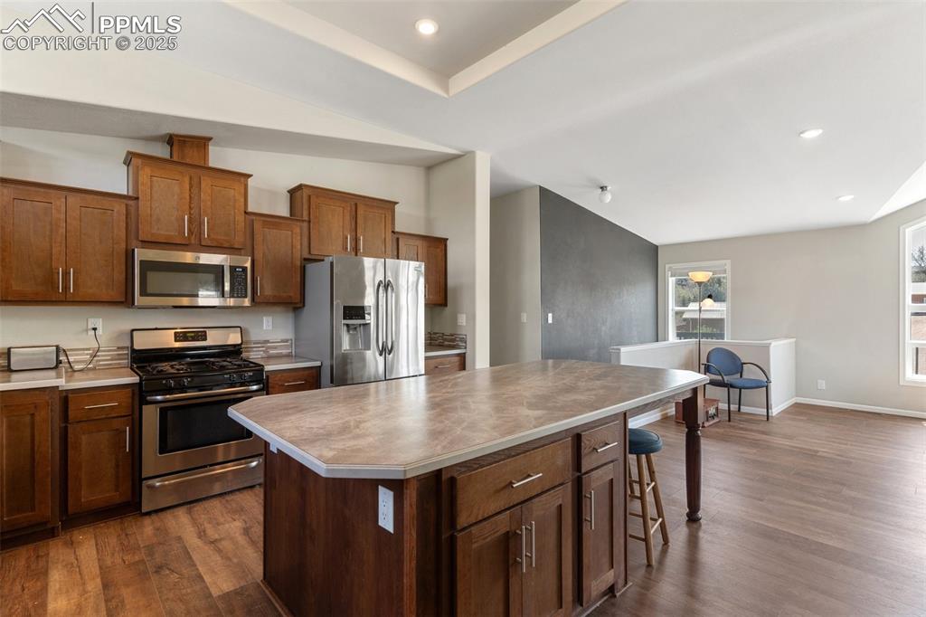 Image 14 of 50: Kitchen with vaulted ceiling, a center island, appliances with stainless st