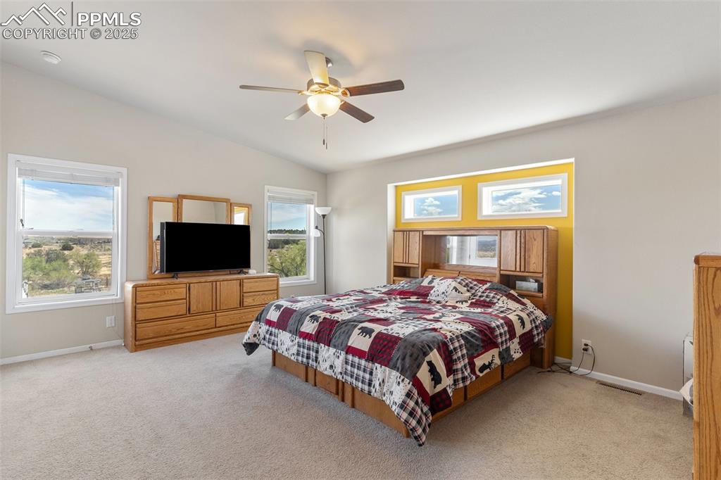 Image 17 of 50: Bedroom featuring lofted ceiling, baseboards, light colored carpet, and vis