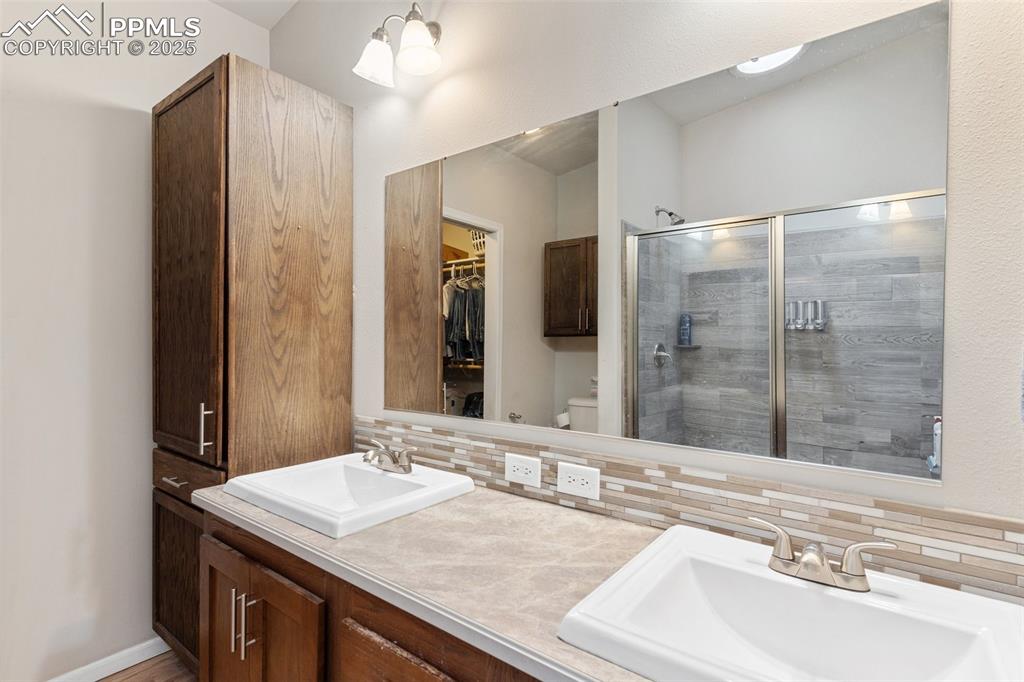 Image 19 of 50: Full bath with backsplash, a sink, and a stall shower