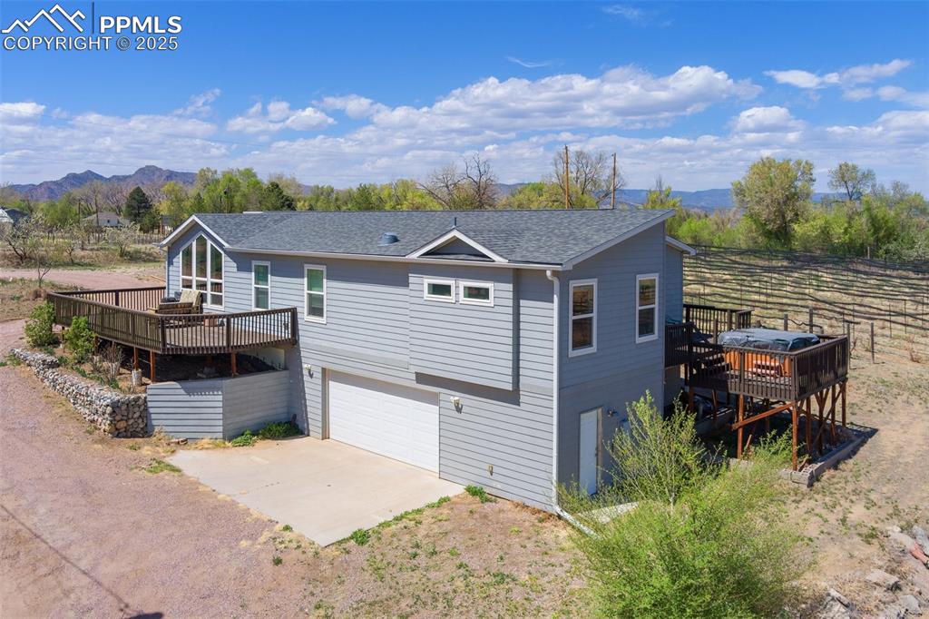 Image 2 of 50: View of front of property featuring an attached garage, driveway, a deck wi