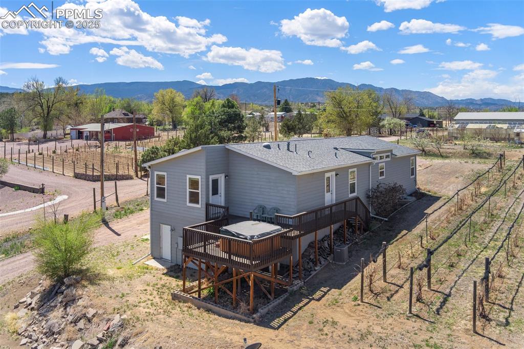 Image 3 of 50: Back of house featuring fence, roof with shingles, a deck with mountain vie