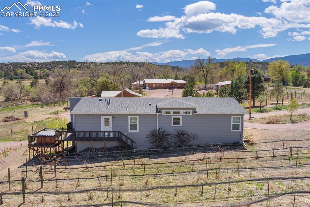 Image 4 of 50: Rear view of property featuring fence, a shingled roof, and a deck with mou
