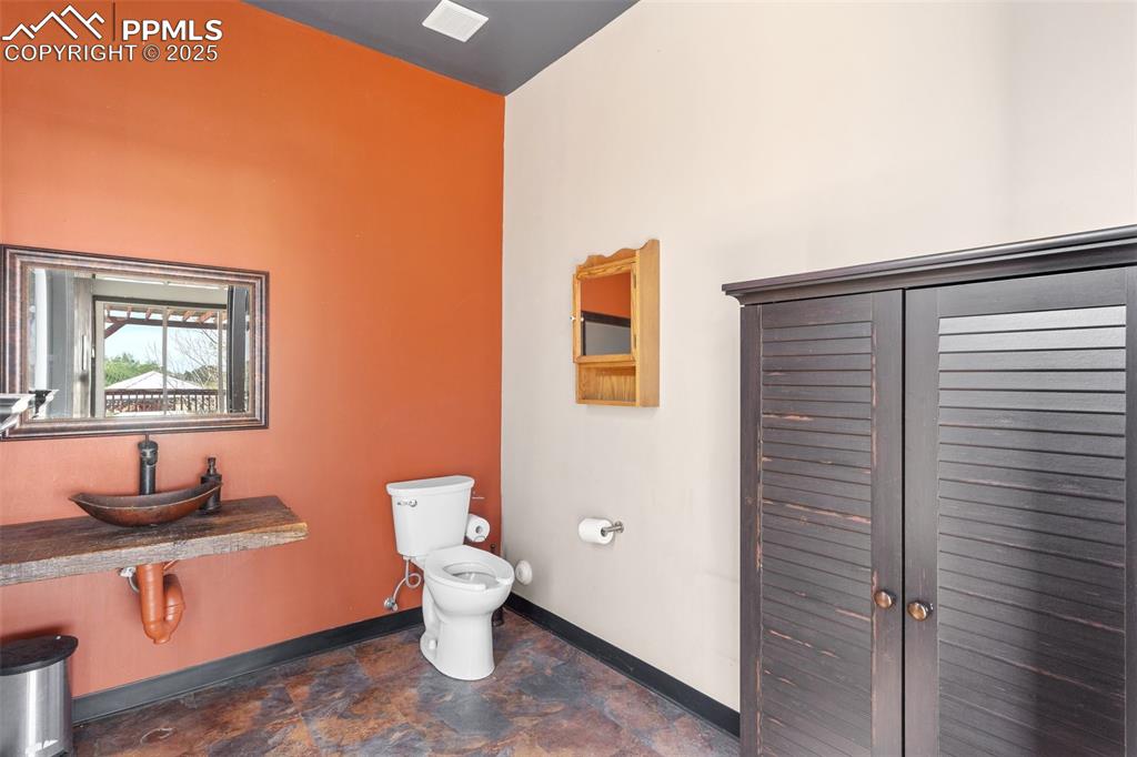 Image 42 of 50: Bathroom with stone finish floor, toilet, and baseboards