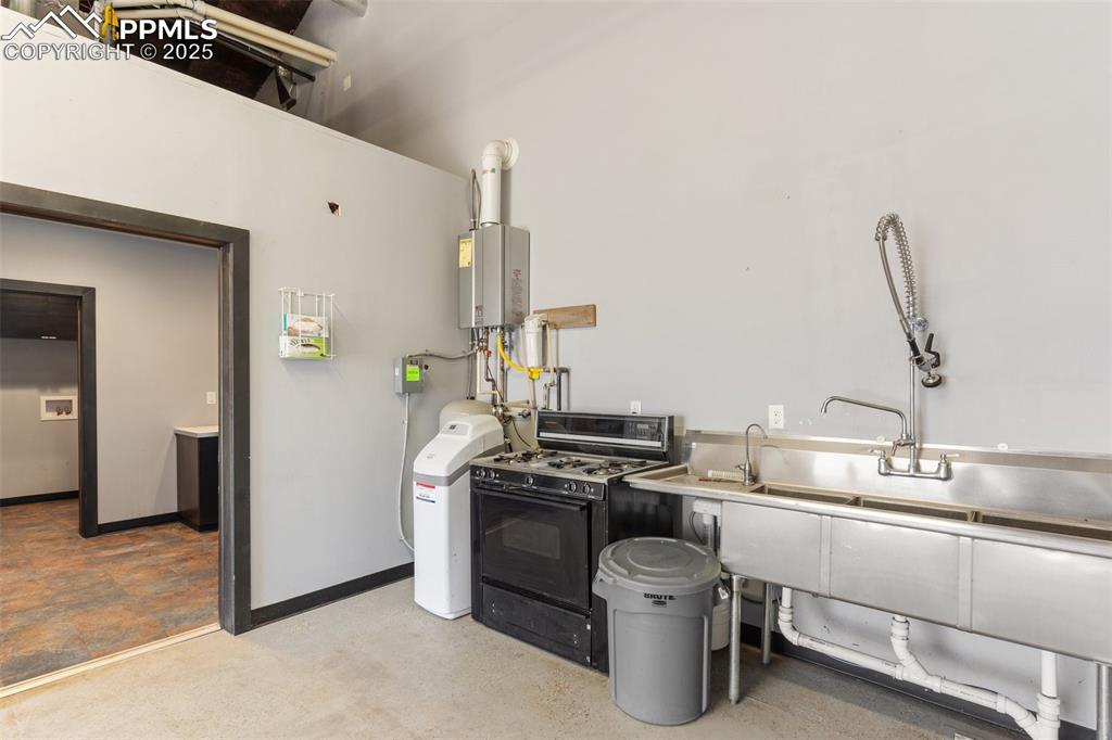 Image 44 of 50: Kitchen featuring baseboards, tankless water heater, and black range with g