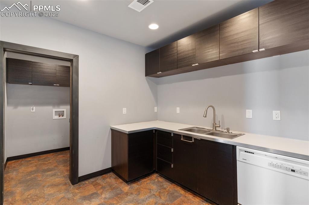Image 45 of 50: Kitchen with light countertops, visible vents, a sink, white dishwasher, an