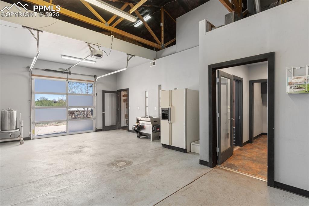 Image 47 of 50: Garage featuring visible vents, white refrigerator with ice dispenser, and 