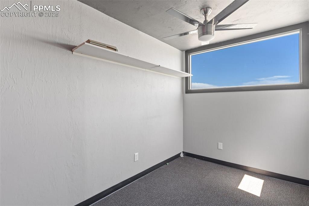 Image 49 of 50: Empty room with a ceiling fan and baseboards