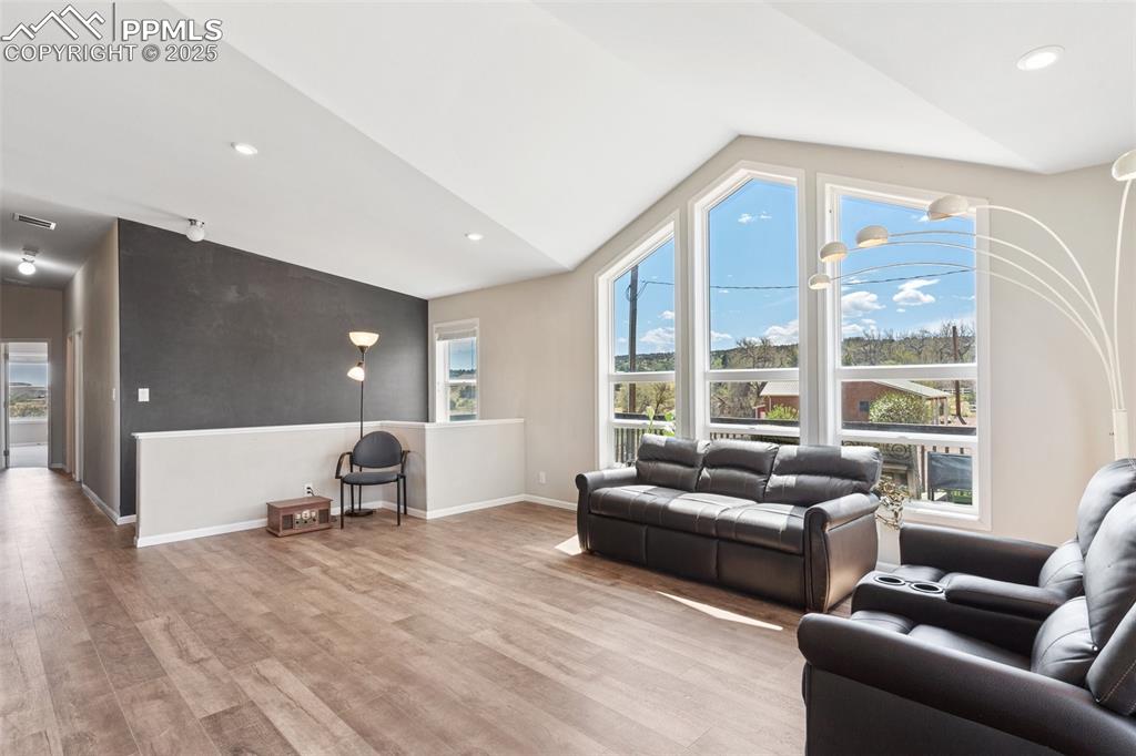 Image 6 of 50: Living area featuring vaulted ceiling, wood finished floors, baseboards, vi