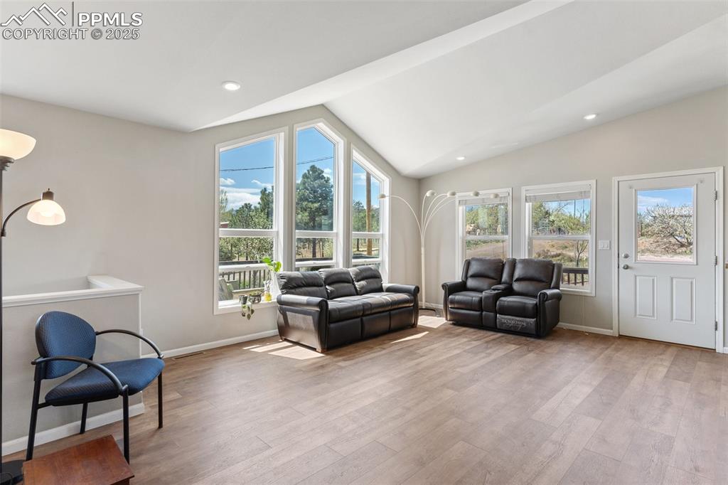 Image 8 of 50: Living area with recessed lighting, lofted ceiling, baseboards, and wood fi