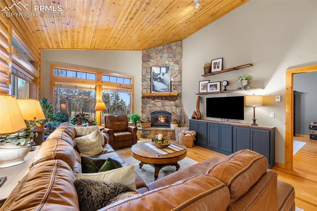 Image 10 of 34: Anchored by a beautiful stone fireplace, this living space offers soaring c