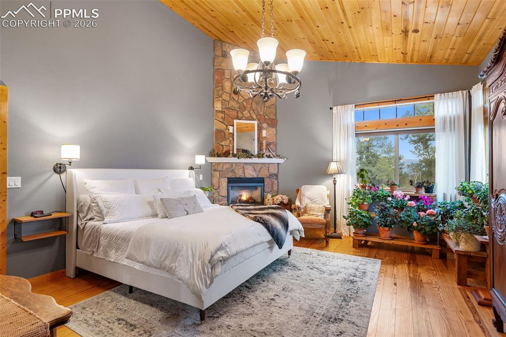 Image 11 of 34: Peaceful and inviting, the primary suite features a stone fireplace, vaulte