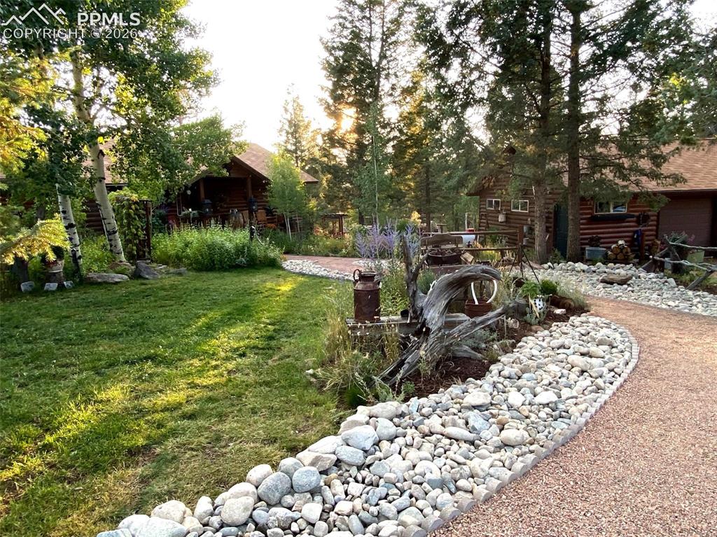Image 20 of 34: Beautifully landscaped, the grounds feature a winding path, mature trees, a