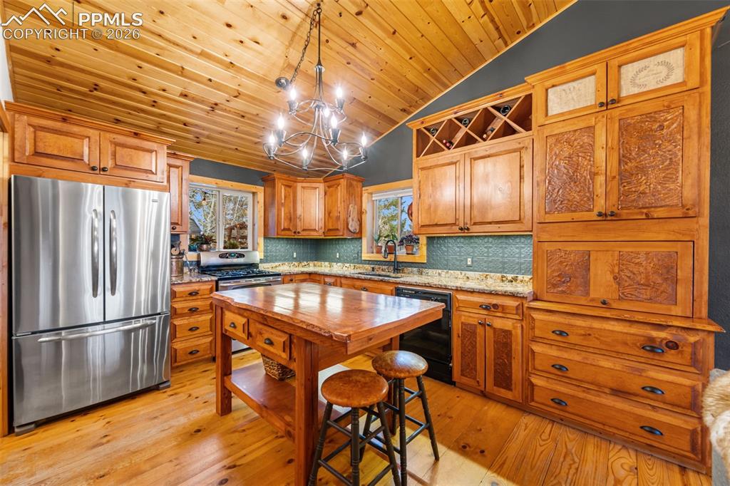 Image 5 of 34: Warm and inviting, the kitchen features custom wood cabinetry, granite coun