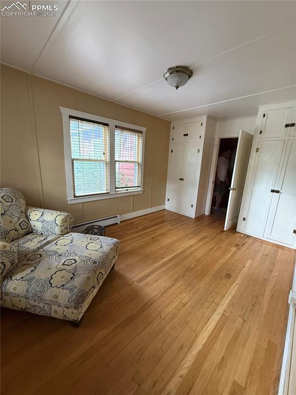 Image 12 of 23: Living area featuring a baseboard heating unit and light wood-style floorin