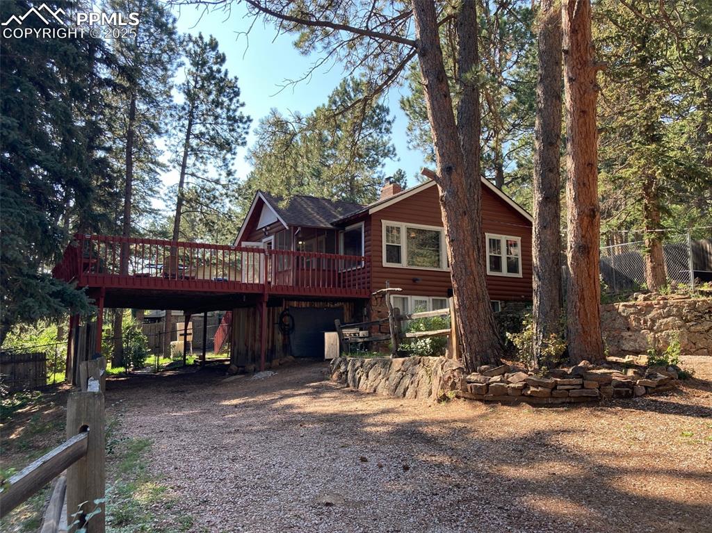 Image 2 of 23: Rear view of property with a wooden deck, a chimney, driveway, a carport, a