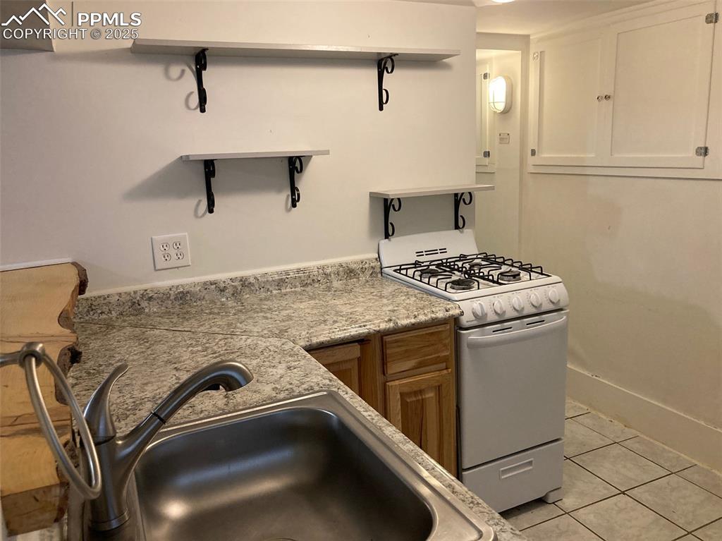 Image 20 of 23: Kitchen featuring white range with gas stovetop, light tile patterned floor