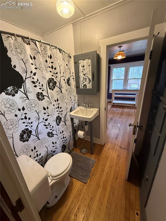 Image 7 of 23: Bathroom with wood-type flooring and curtained shower