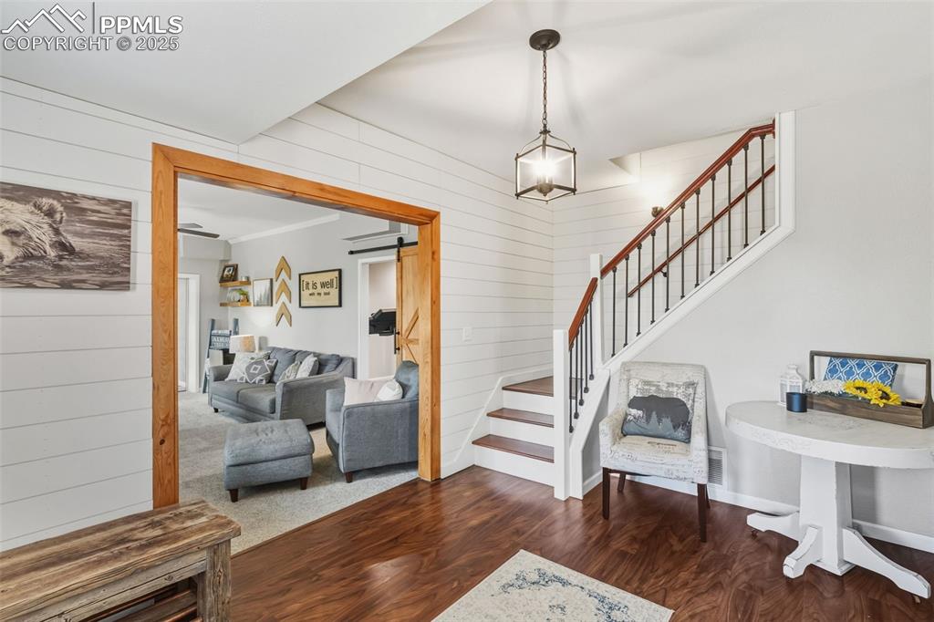 Image 6 of 33: Cozy foyer with updated staircase and shiplap walls