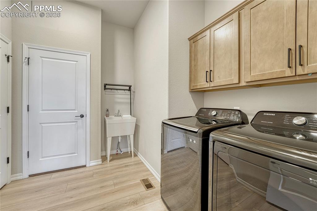 Image 27 of 50: Mudroom and laundry, off of garage with sink and cabinetry.