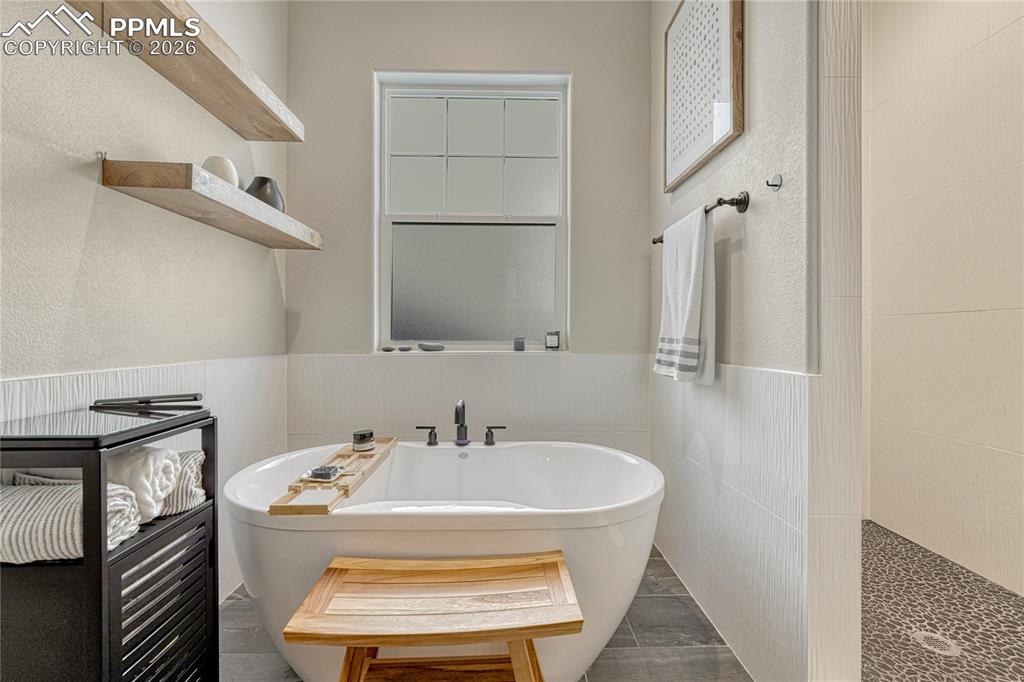 Image 6 of 50: relaxing soaking tub with large walk-in shower in primary en suite