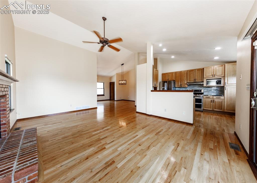 Image 10 of 44: Unfurnished living room with vaulted ceiling, a fireplace, light wood-type 