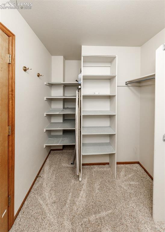 Image 23 of 44: Walk in closet featuring light colored carpet
