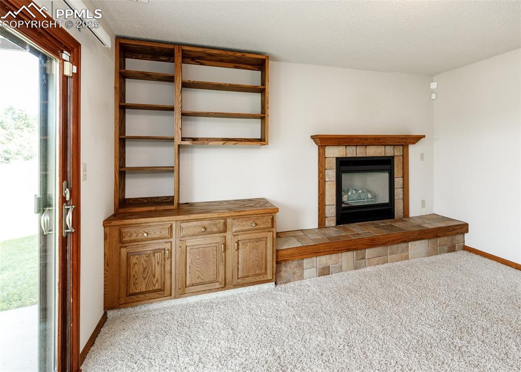 Image 28 of 44: Unfurnished living room with light colored carpet, a tile fireplace, and a 