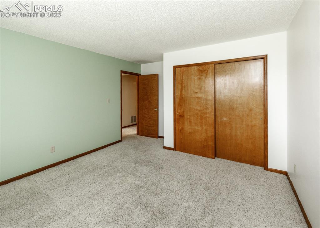 Image 30 of 44: Unfurnished bedroom featuring carpet flooring, a textured ceiling, and a cl