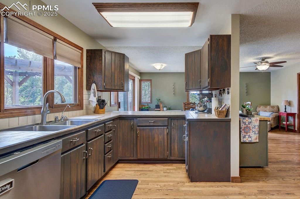 Image 11 of 42: Kitchen with a sink, light wood-style flooring, dishwasher, and dark brown