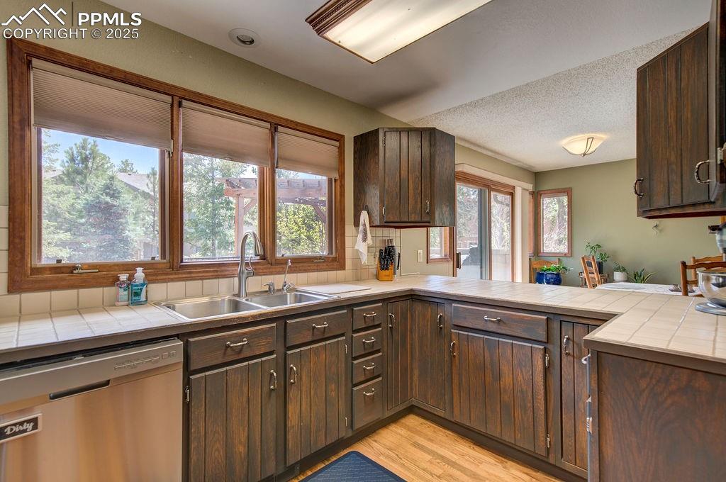 Image 13 of 42: Kitchen with a sink, stainless steel dishwasher, and dark brown cabinetry