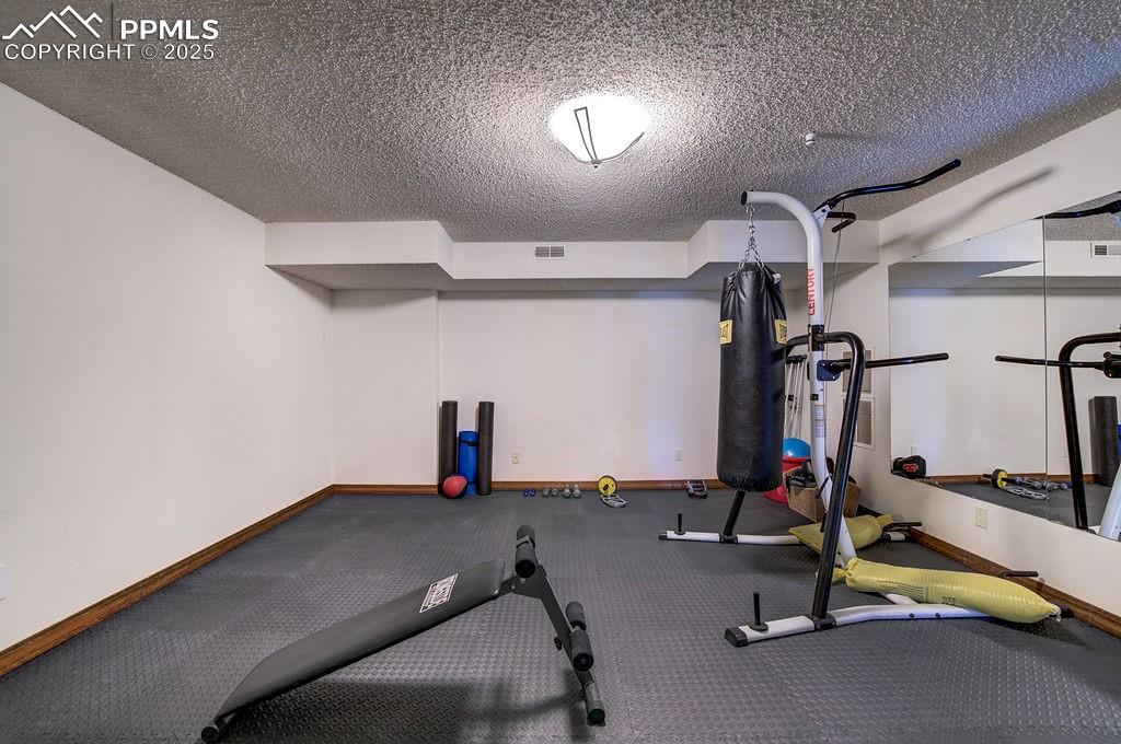 Image 19 of 42: Workout room with baseboards, a textured ceiling, and visible vents
