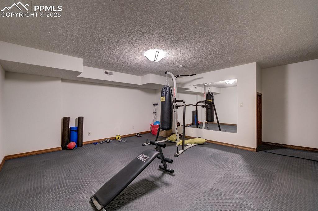 Image 20 of 42: Exercise area featuring a textured ceiling, baseboards, and visible vents