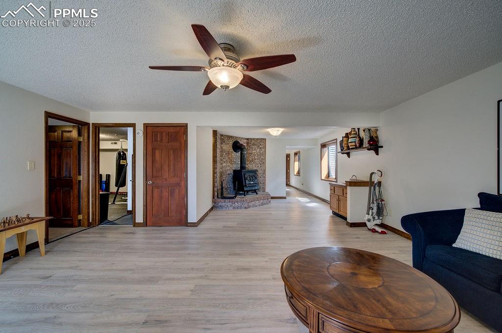 Image 22 of 42: Living room with a ceiling fan, a textured ceiling, light wood-style floori