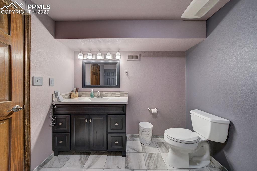 Image 23 of 42: Bathroom featuring baseboards, marble finish floor, toilet, and visible ven