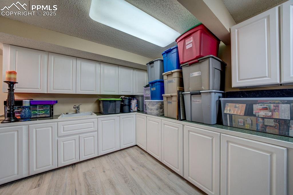 Image 24 of 42: Kitchen featuring light wood-style floors, a sink, a textured ceiling, and