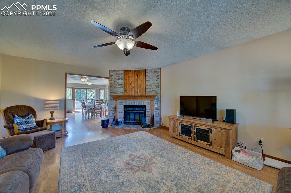 Image 25 of 42: Living room featuring a ceiling fan, a textured ceiling, and wood finished