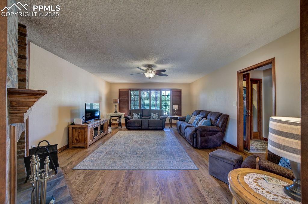 Image 3 of 42: Living area featuring a ceiling fan, a textured ceiling, wood finished floo