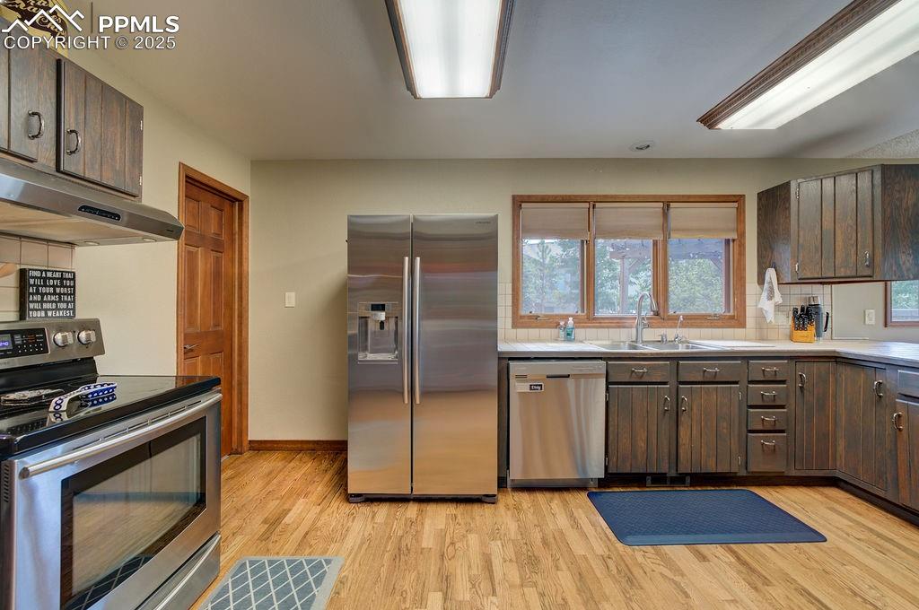 Image 31 of 42: Kitchen with dark brown cabinetry, appliances with stainless steel finishes