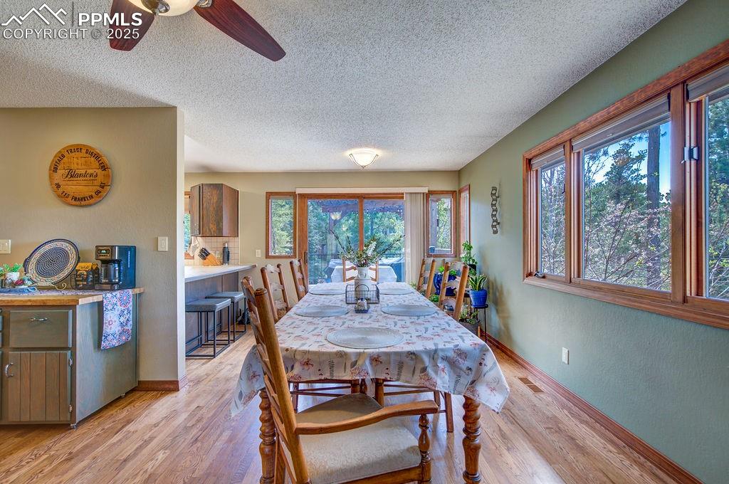 Image 32 of 42: Dining room with a ceiling fan, a textured ceiling, and light wood-type flo