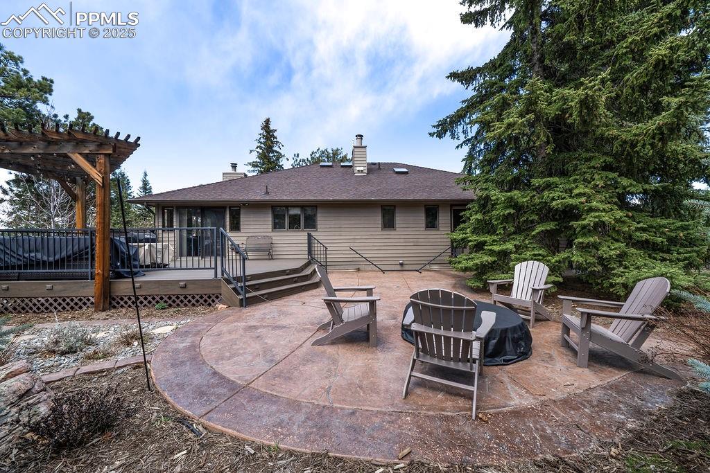 Image 34 of 42: Rear view of property featuring a wooden deck, a chimney, an outdoor fire p