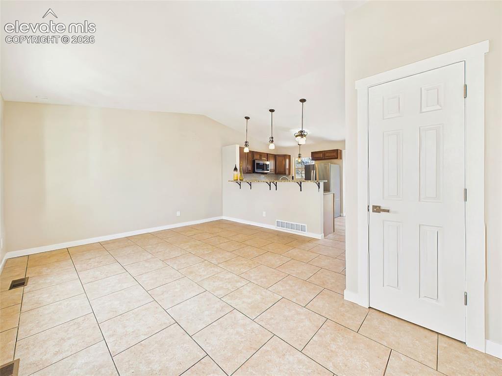 Image 10 of 50: Welcoming main-level living area offering vaulted ceilings, expansive tile