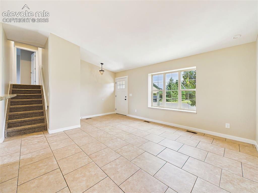 Image 12 of 50: Spacious open-concept living area with large-format tile floors, expansive