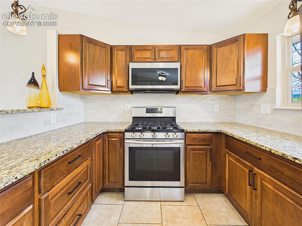 Image 15 of 50: Chef-inspired kitchen featuring rich wood cabinetry, granite countertops, s
