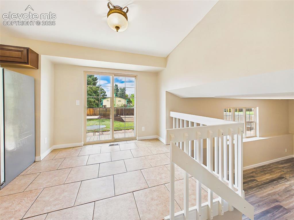 Image 18 of 50: Open dining area with vaulted ceilings, tile flooring, sliding glass door t