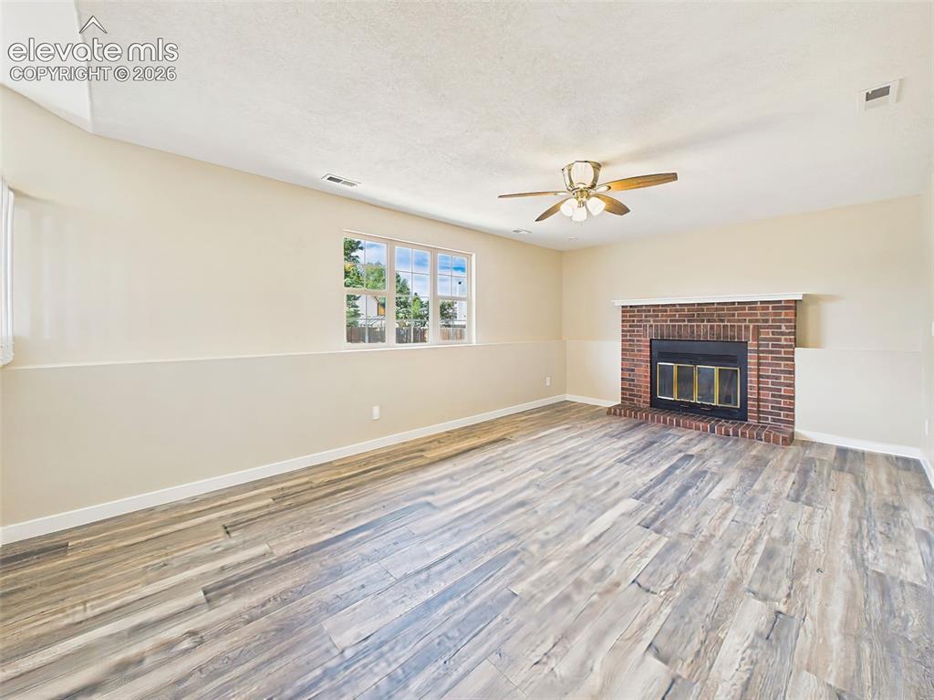 Image 20 of 50: Warm and welcoming lower-level family room with a charming brick fireplace,