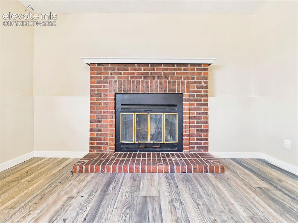 Image 23 of 50: Charming brick fireplace with raised hearth and mantel serves as the focal